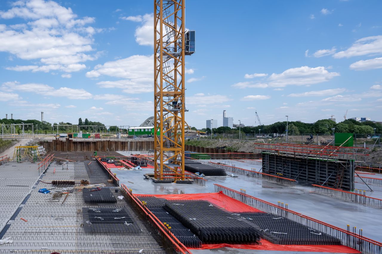A vibrant construction site with a prominent yellow tower crane under a bright blue sky.